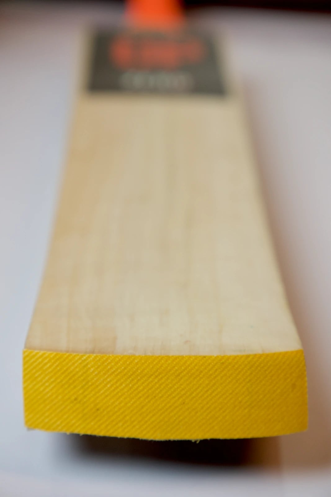 Close-up of the toe end of the blade with yellow material across the toe, the face and its grain receding out of focus towards the label